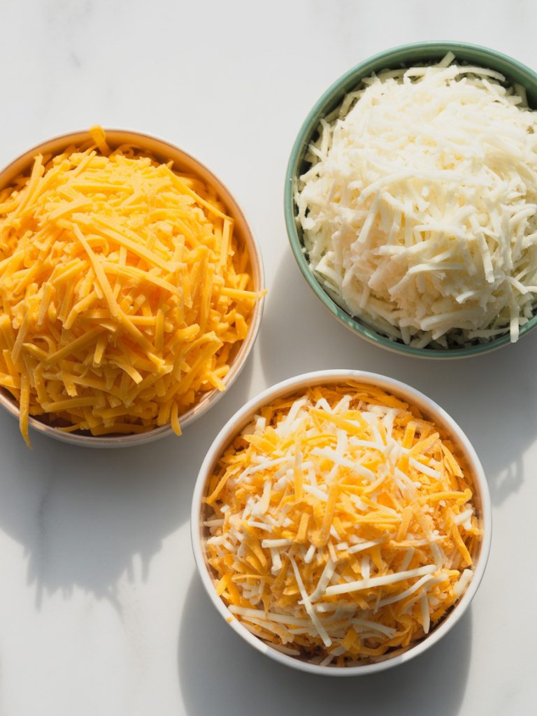 Three bowls showing different shredded cheese types for quesadillas including cheddar and Monterey Jack