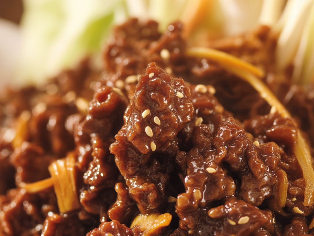 Macro close-up of Korean ground beef showing glossy brown sauce coating and sesame seeds
