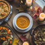 Assortment of fall dinner recipes including butternut squash soup, pot pie, and roasted vegetables on rustic wooden table with autumn leaves