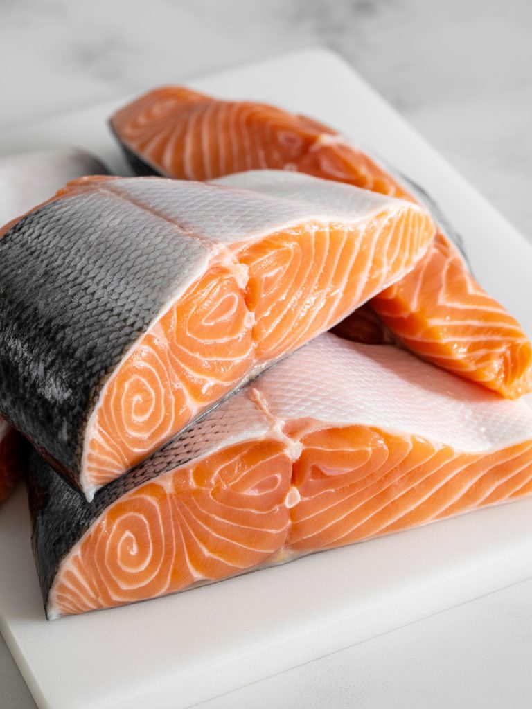 Close-up of fresh raw salmon fillets with silver skin showing bright pink-orange flesh and marbling