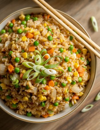 Colorful bowl of homemade fried rice with vegetables, scrambled eggs and green onions garnish with chopsticks