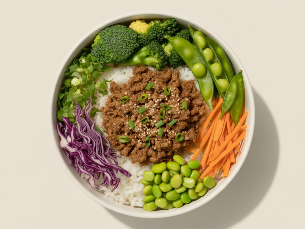 Colorful Korean beef bowl with broccoli, snap peas, cabbage, carrots and edamame arranged in white bowl