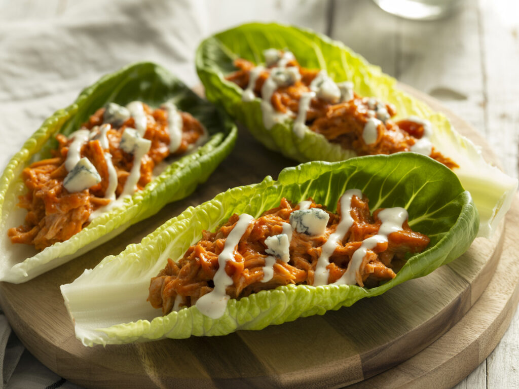 Buffalo chicken lettuce wraps with blue cheese and ranch dressing on wooden board