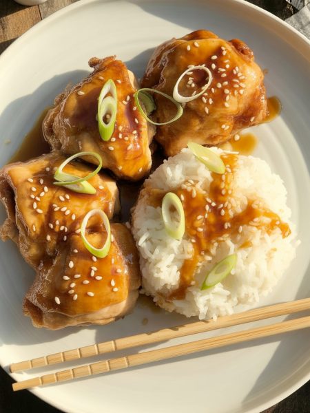 Golden-brown honey teriyaki chicken thighs with glossy amber glaze, garnished with sesame seeds and green onions, served with rice
