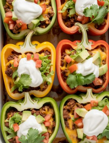 Overhead view of taco stuffed peppers with melted cheese and Mexican toppings in baking dish