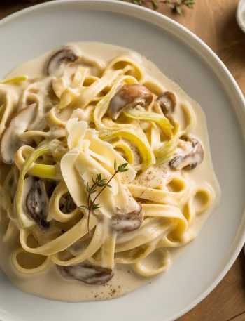 Elegant pasta with caramelized leeks, mushrooms, and Gruyere cheese in creamy sauce topped with fresh thyme