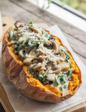 Baked sweet potato split open and filled with creamy mushroom spinach mixture