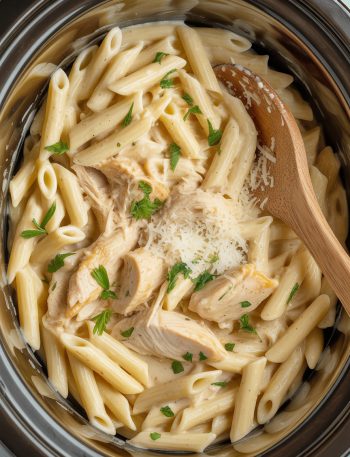 Creamy garlic parm chicken pasta in slow cooker crock pot with parmesan sauce and fresh herbs