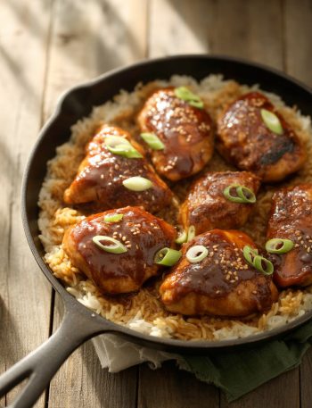 One-pan honey BBQ chicken and rice with glazed chicken pieces over fluffy rice garnished with green onions