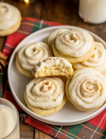 Soft eggnog cookies topped with creamy eggnog frosting and nutmeg on festive holiday plate