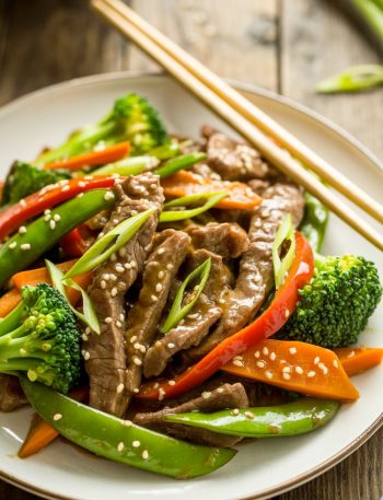 Asian sweet ginger beef stir fry with vegetables on white plate