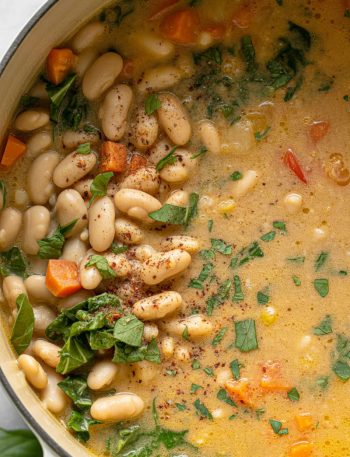 Pot of creamy Tuscan white bean soup with beans, kale, carrots in rich velvety broth