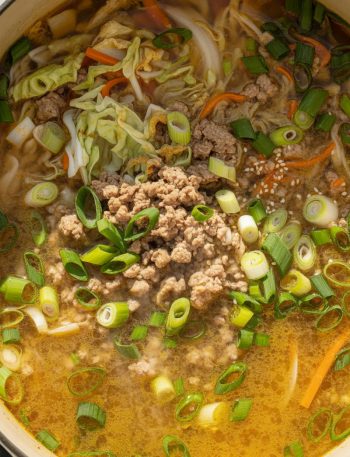 Pot of egg roll soup with ground pork, cabbage, carrots, and green onions in savory broth