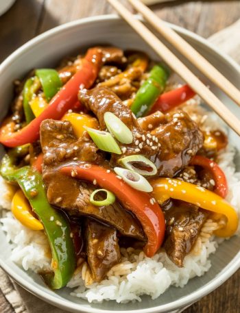 Pepper steak with colorful bell peppers in white bowl over rice