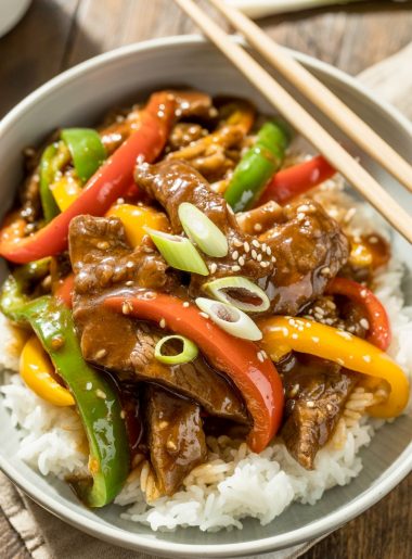 Pepper steak with colorful bell peppers in white bowl over rice