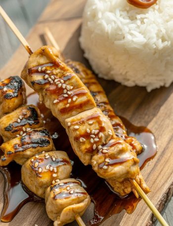 Japanese chicken yakitori skewers with glossy tare sauce on wooden board with rice