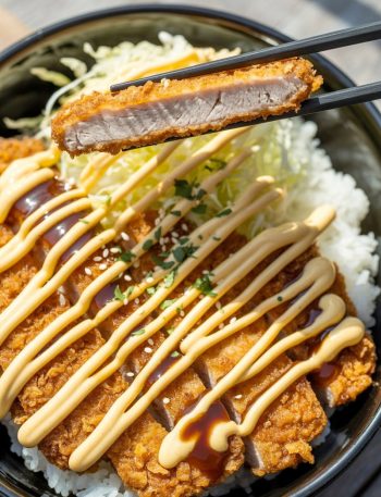 Japanese katsu bowl with crispy breaded cutlet and tonkatsu sauce drizzle over rice