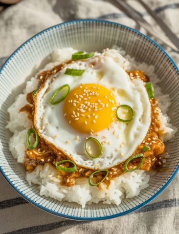 Korean egg rice bowl with fried egg on top and green onions in striped bowl