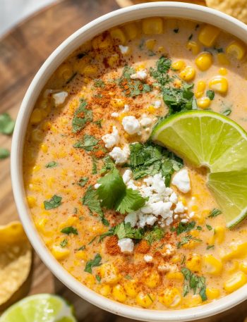 Bowl of creamy Mexican street corn soup topped with cotija cheese, cilantro, and lime