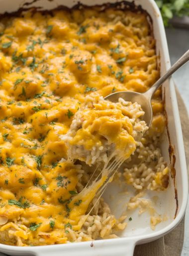 Golden bubbly chicken rice casserole with melted cheddar cheese, fresh parsley garnish, and cheese pull from serving spoon