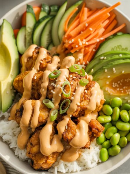 Bang Bang Chicken Bowl with crispy chicken, creamy sauce, rice and fresh vegetables in white bowl