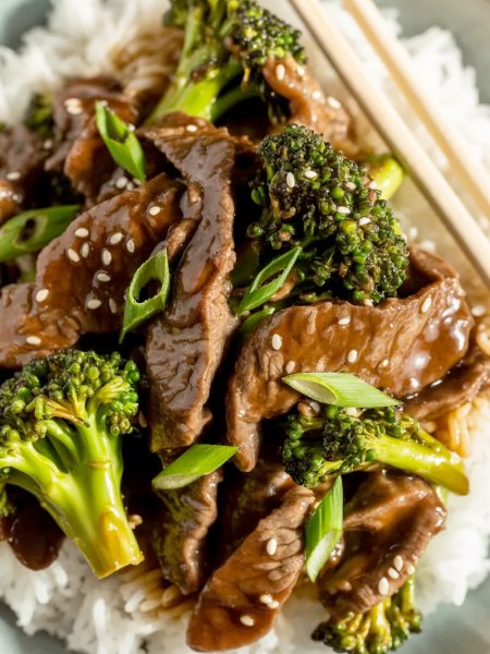 Beef and broccoli stir-fry with glossy sauce over white rice garnished with sesame seeds