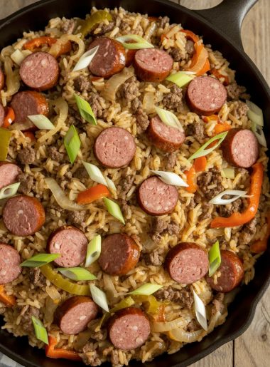 Close-up of jailhouse rice in a cast iron skillet loaded with sliced smoked sausage, ground beef, bell peppers, and green onion garnish