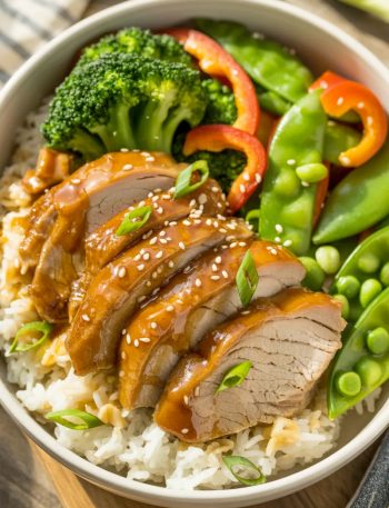 Rice bowl with sliced honey garlic glazed pork, steamed broccoli, bell peppers, sesame seeds, and green onions
