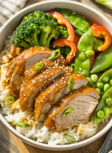 Rice bowl with sliced honey garlic glazed pork, steamed broccoli, bell peppers, sesame seeds, and green onions