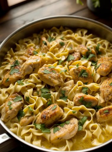 Golden seared chicken pieces and tender egg noodles in a rich creamy garlic butter sauce in a large skillet garnished with fresh parsley