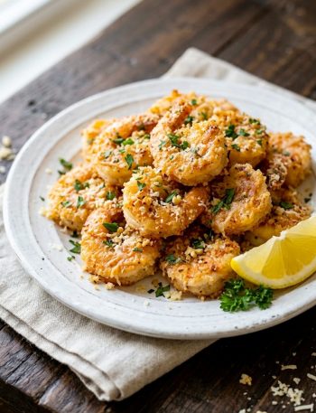 Crispy air fryer garlic parmesan shrimp on a white plate garnished with fresh parsley