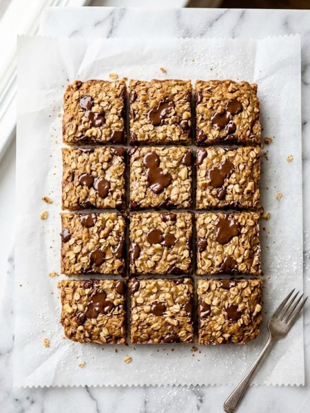 Close-up of sliced banana bread oatmeal bars with chocolate chips on a white marble surface