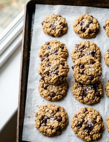 Five-ingredient healthy peanut butter oatmeal cookies with chocolate chips and flaky sea salt on parchment paper