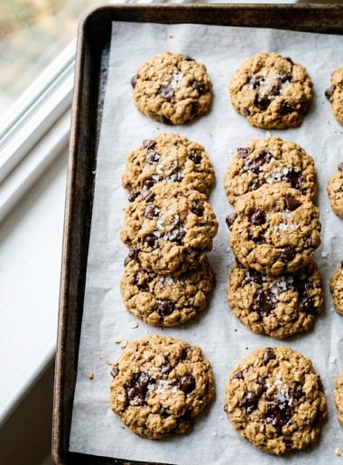 Five-ingredient healthy peanut butter oatmeal cookies with chocolate chips and flaky sea salt on parchment paper