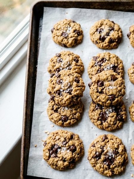 Five-ingredient healthy peanut butter oatmeal cookies with chocolate chips and flaky sea salt on parchment paper