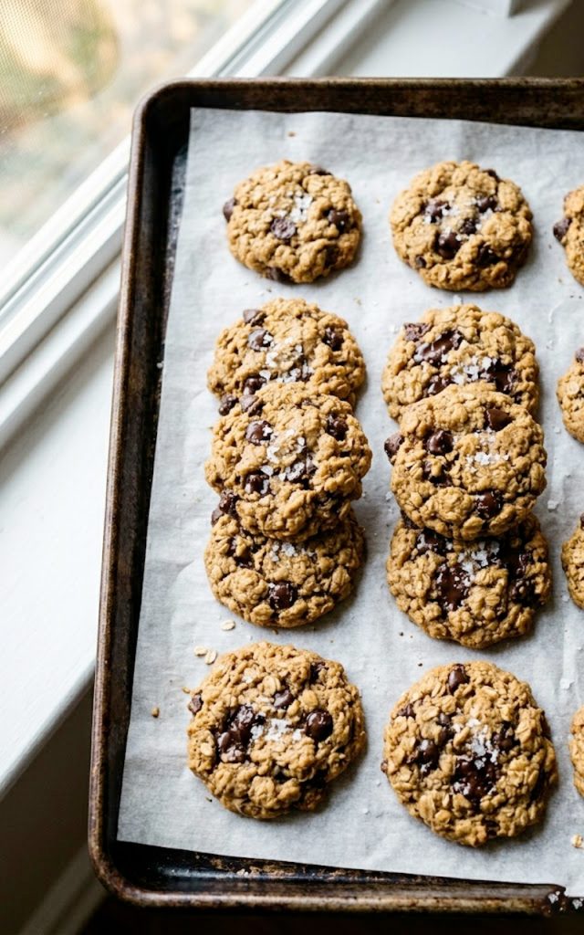 Five-ingredient healthy peanut butter oatmeal cookies with chocolate chips and flaky sea salt on parchment paper