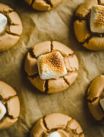 A tray of freshly baked peanut butter marshmallow cookies with gooey melted marshmallow on parchment paper