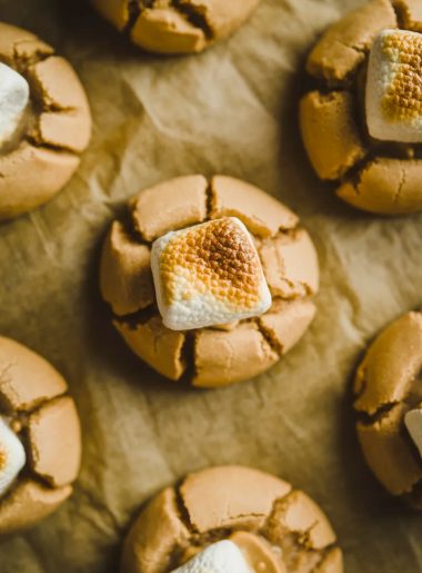 A tray of freshly baked peanut butter marshmallow cookies with gooey melted marshmallow on parchment paper