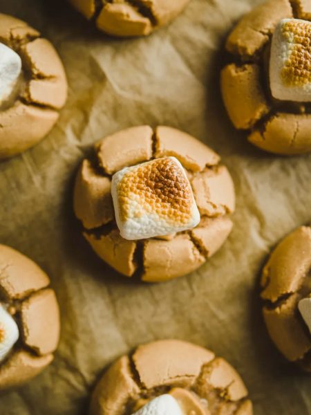 A tray of freshly baked peanut butter marshmallow cookies with gooey melted marshmallow on parchment paper