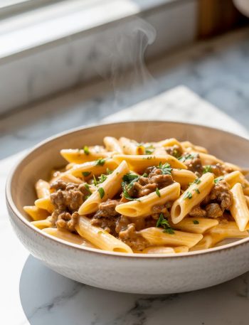 A bowl of quick creamy beef pasta topped with ground beef, creamy cheese sauce and fresh parsley