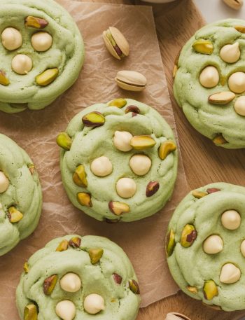 Close-up of soft green pistachio pudding cookies with white chocolate chips on parchment paper