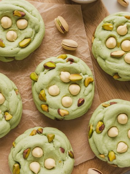 Close-up of soft green pistachio pudding cookies with white chocolate chips on parchment paper