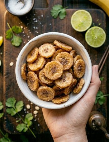 Crispy golden cinnamon sugar air fryer banana chips piled high in a small rustic ceramic bowl on a wooden surface