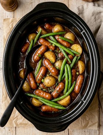 Crockpot Lil Smokies, potatoes and green beans coated in a rich savory-sweet sauce inside a black slow cooker