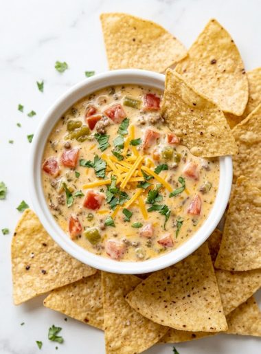 Overhead view of creamy Rotel cheese dip in a white ramekin garnished with cilantro and surrounded by tortilla chips on a marble surface
