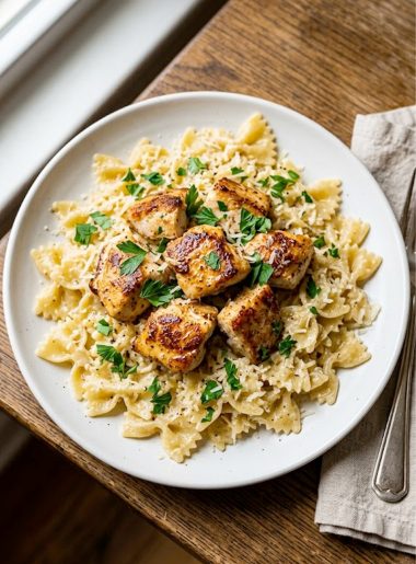 Garlic butter chicken with bowtie pasta served on a white plate garnished with fresh parsley