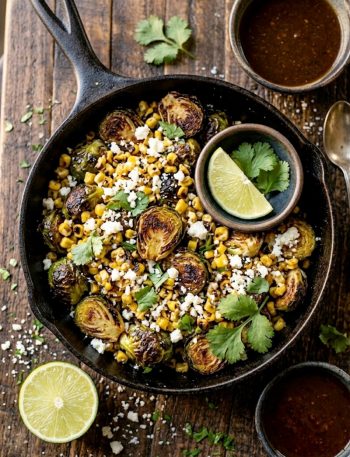 Crispy roasted Brussels sprouts and charred corn tossed with street corn sauce, cotija cheese, and fresh cilantro in a black cast iron skillet