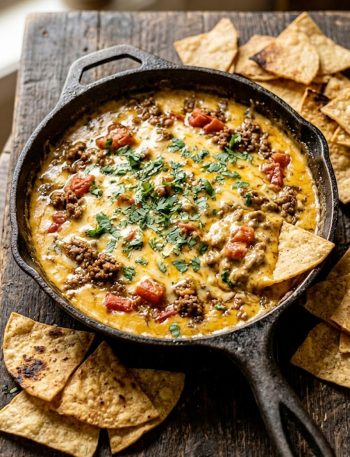 Overhead view of Rotel dip with ground beef and tomatoes in a cast iron skillet surrounded by tortilla chips