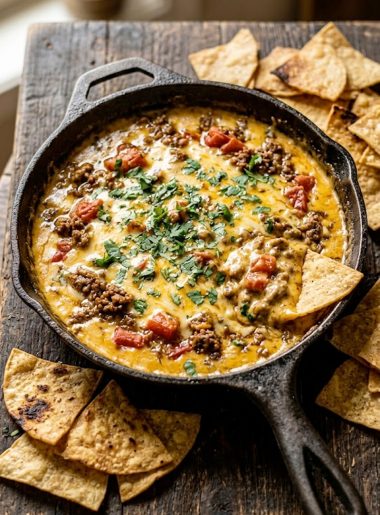 Overhead view of Rotel dip with ground beef and tomatoes in a cast iron skillet surrounded by tortilla chips