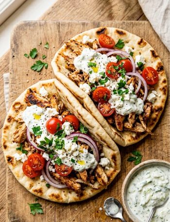 Slow cooker chicken gyros with homemade tzatziki sauce served on warm pita bread with fresh toppings